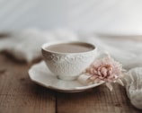 Soft morning light filtering through a window onto a serene tea corner with a simple ceramic teacup and a sprig of fresh flowers.