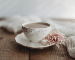 A delicate glass teacup filled with steaming white tea, surrounded by subtle golden light.