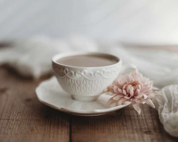 A delicate porcelain teacup resting on a lace doily, bathed in gentle afternoon light.