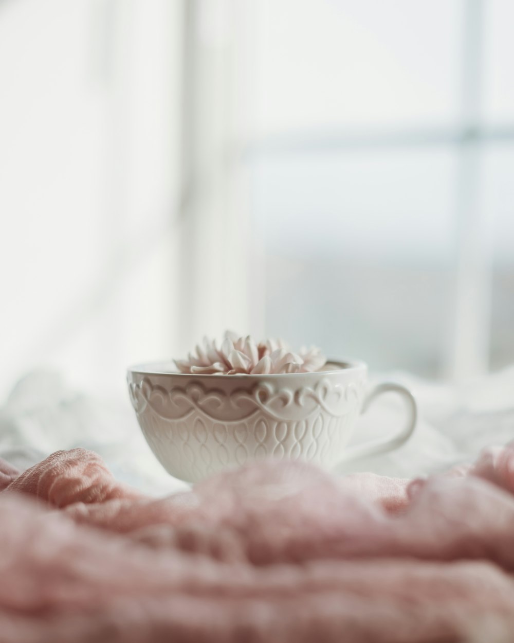 white ceramic teacup on pink textile