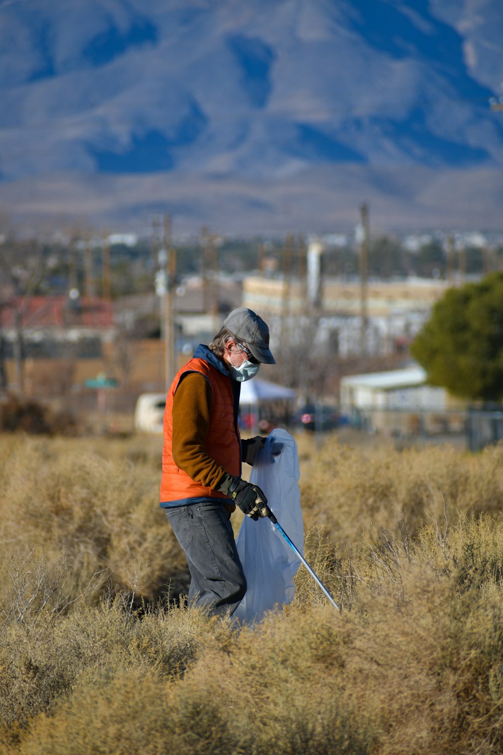 man in orange jacket and black pants with black backpack walking on green grass field during