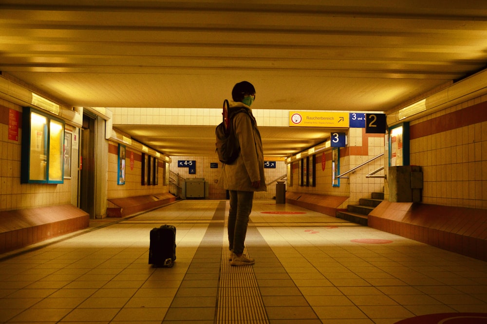 man in brown coat standing on white floor tiles