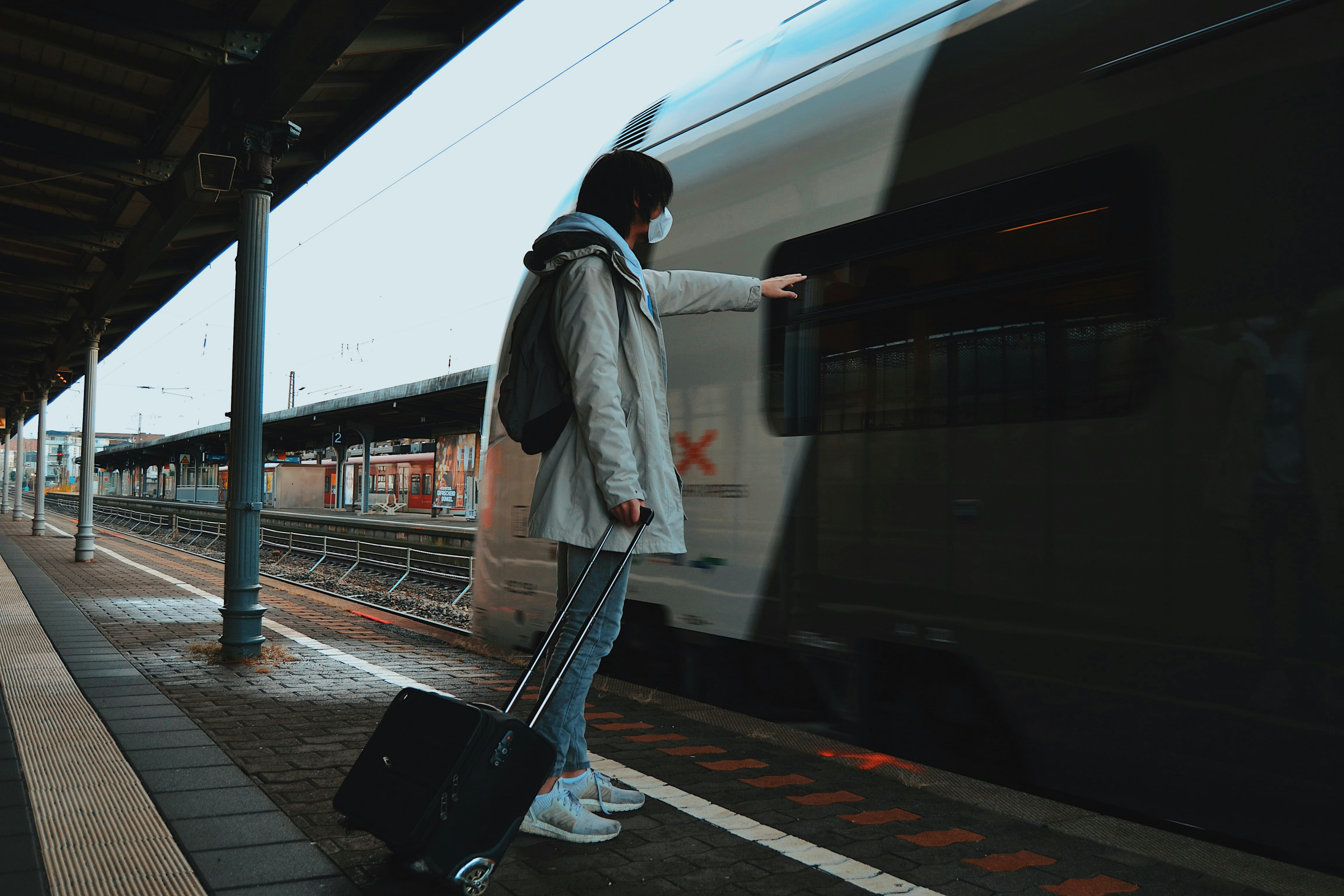 man in gray coat and blue denim jeans walking on sidewalk
