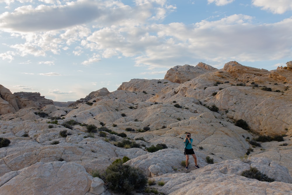 person in blue jacket standing on rocky hill during daytime