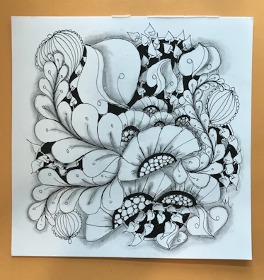 A close-up of intricate line work depicting a floral pattern in monochrome.