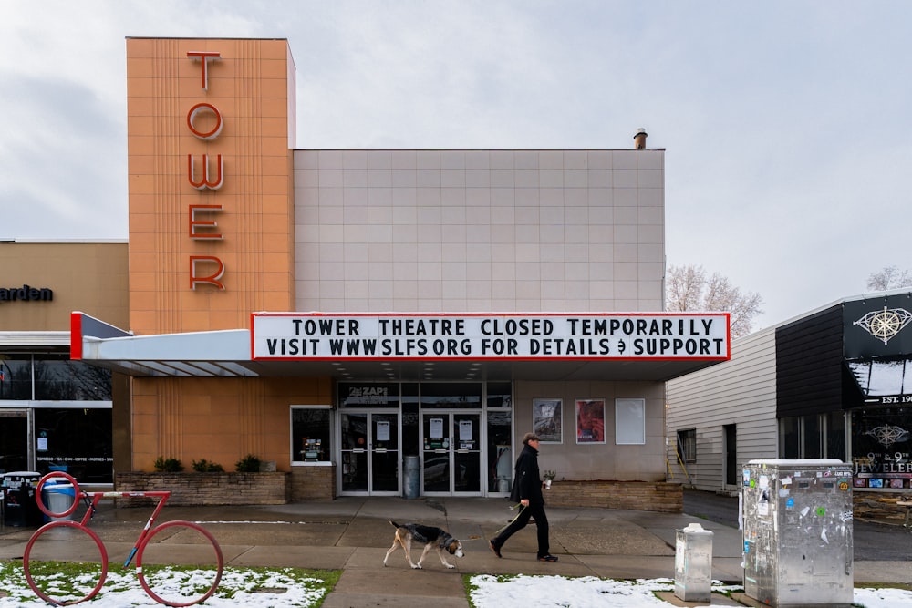 Un hombre paseando a un perro frente a un teatro
