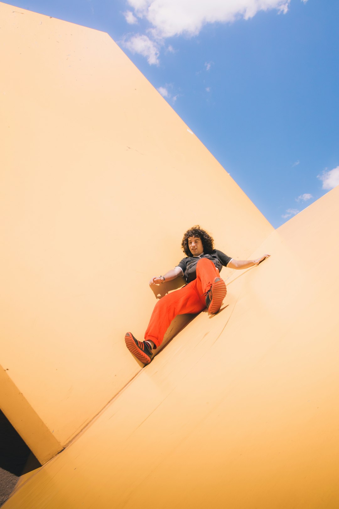 woman in blue and white shirt and red pants sitting on brown sand during daytime