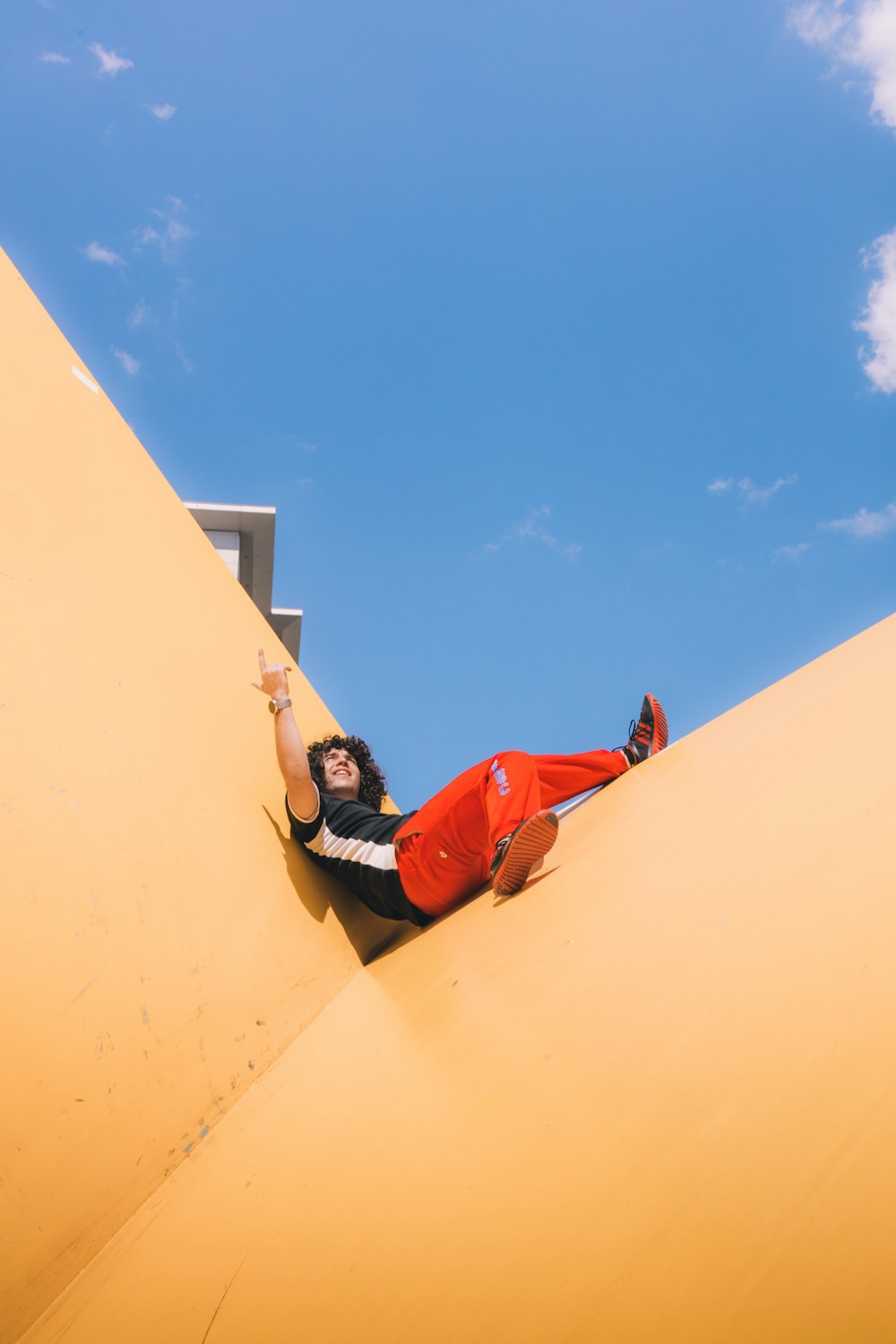 woman in red jacket and black pants lying on beige sand during daytime