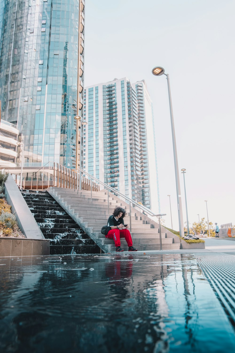 woman in red jacket sitting on water fountain during daytime