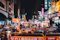 Crowd enjoying live music and colorful food stalls lit by vibrant neon signs at an outdoor night market.