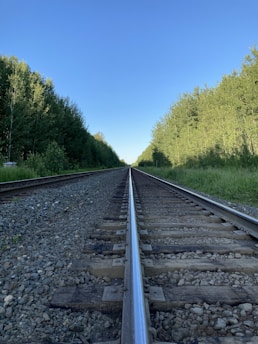 A close-up shot of railway tracks stretching into the distance under a clear blue sky.