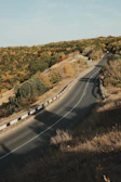A winding road cutting through autumn-colored hills.