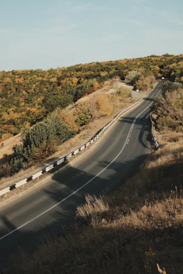 A winding road cutting through autumn-colored hills.