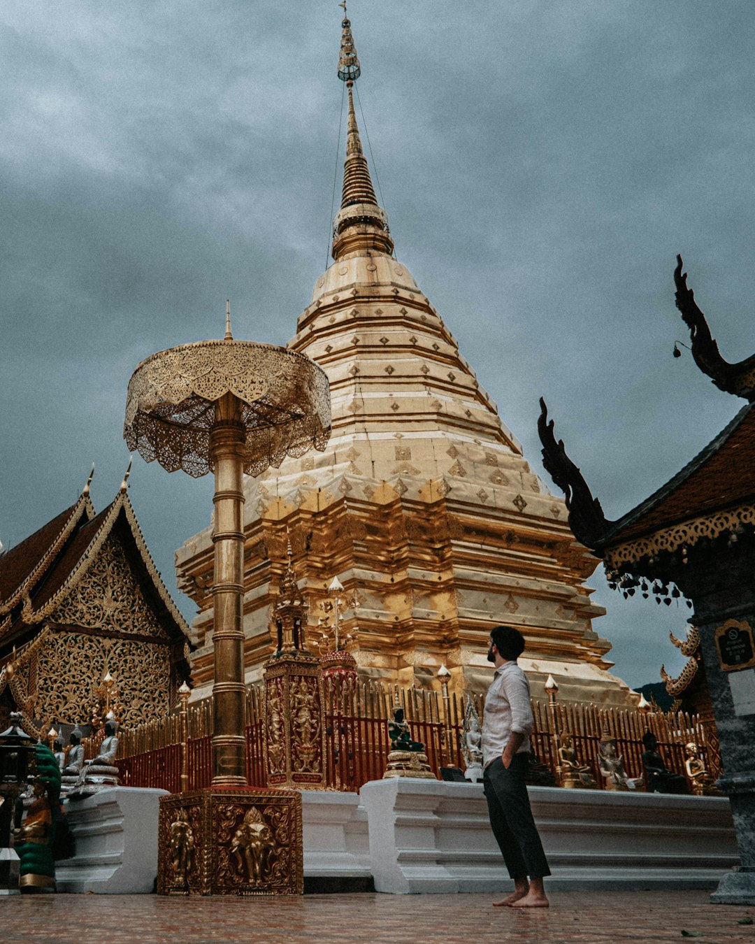 man and woman standing near gold temple under white clouds during daytime