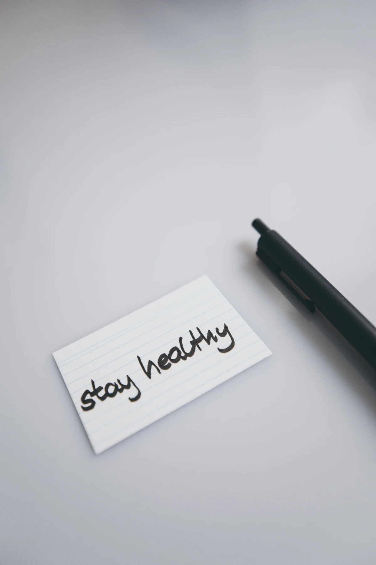 Cartão com a frase em inglês stay healthy, que significa mantenha-se saudável, ao lado de uma caneta.