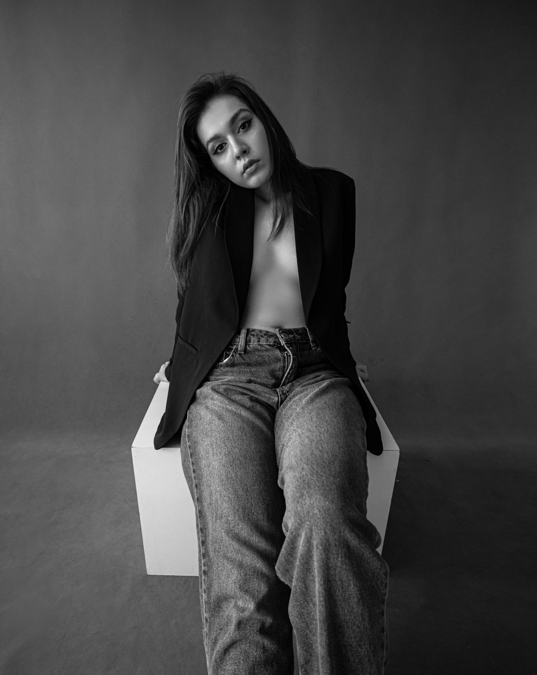 woman in black blazer and blue denim jeans sitting on white chair