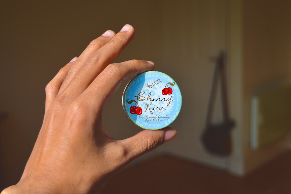 person holding blue and white round container