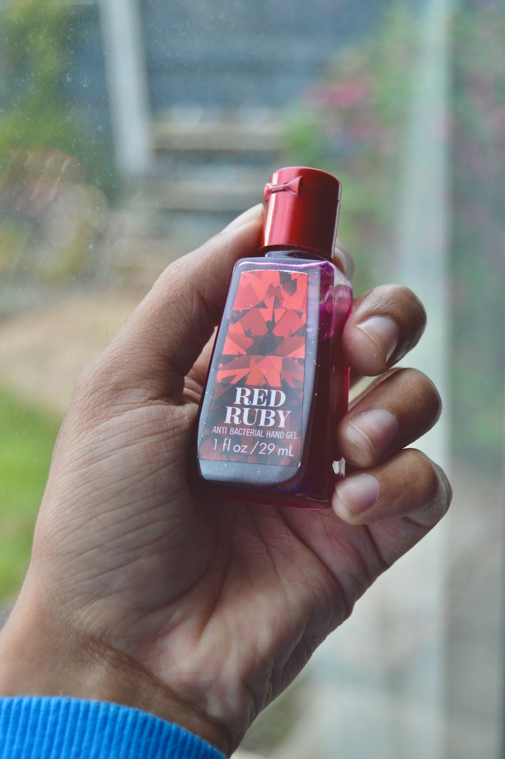 person holding red and black plastic bottle