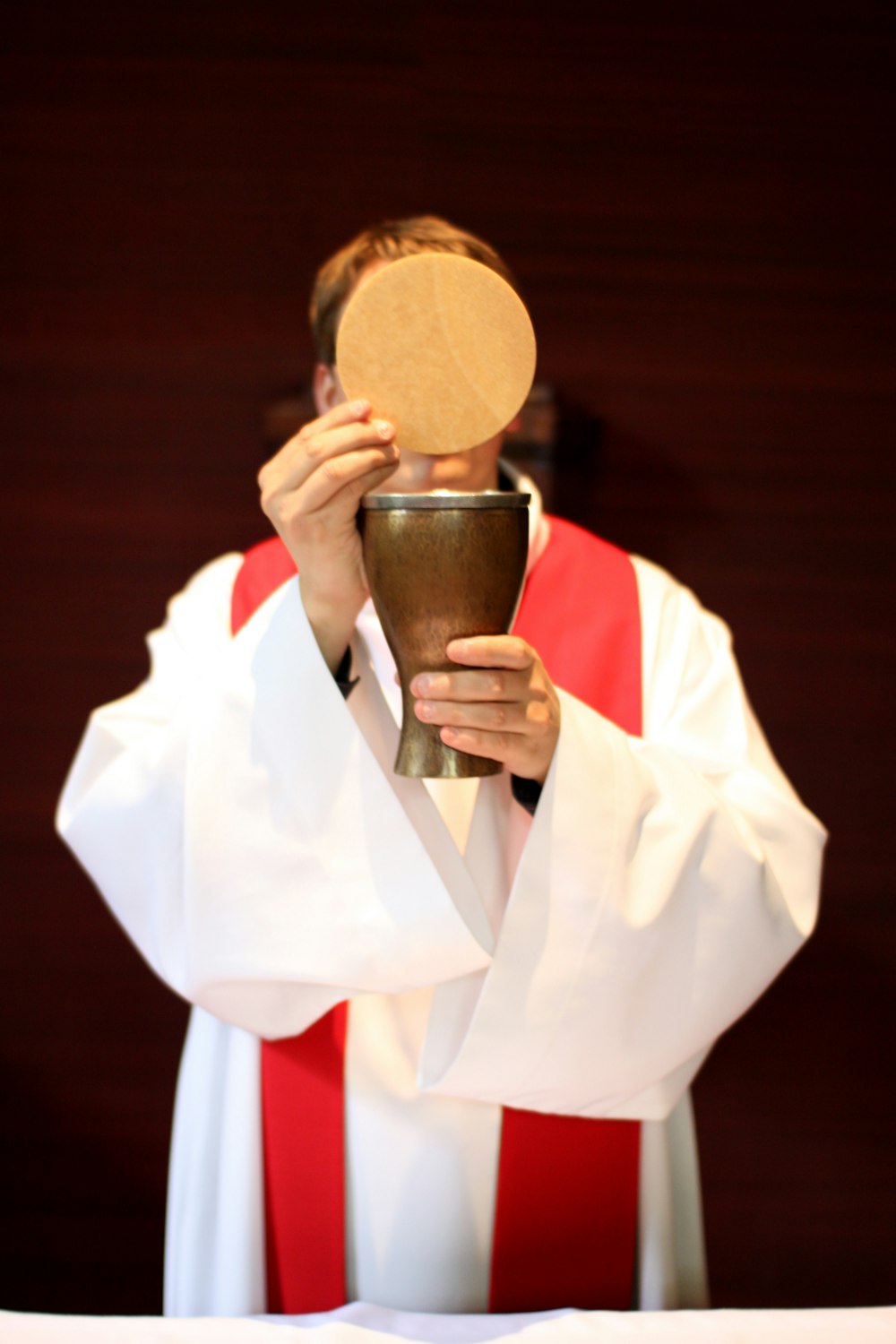 Un hombre con túnicas de sacerdote sosteniendo un cáliz