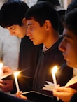 man in black suit jacket holding lighted candle