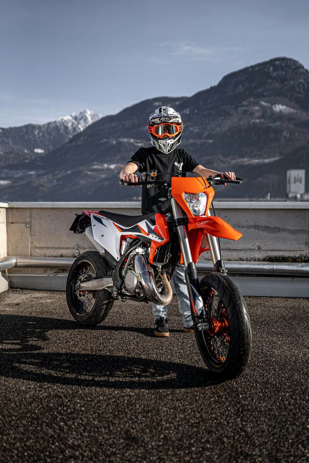 uomo in tuta da motociclista arancione e nera in sella a una moto arancione e nera