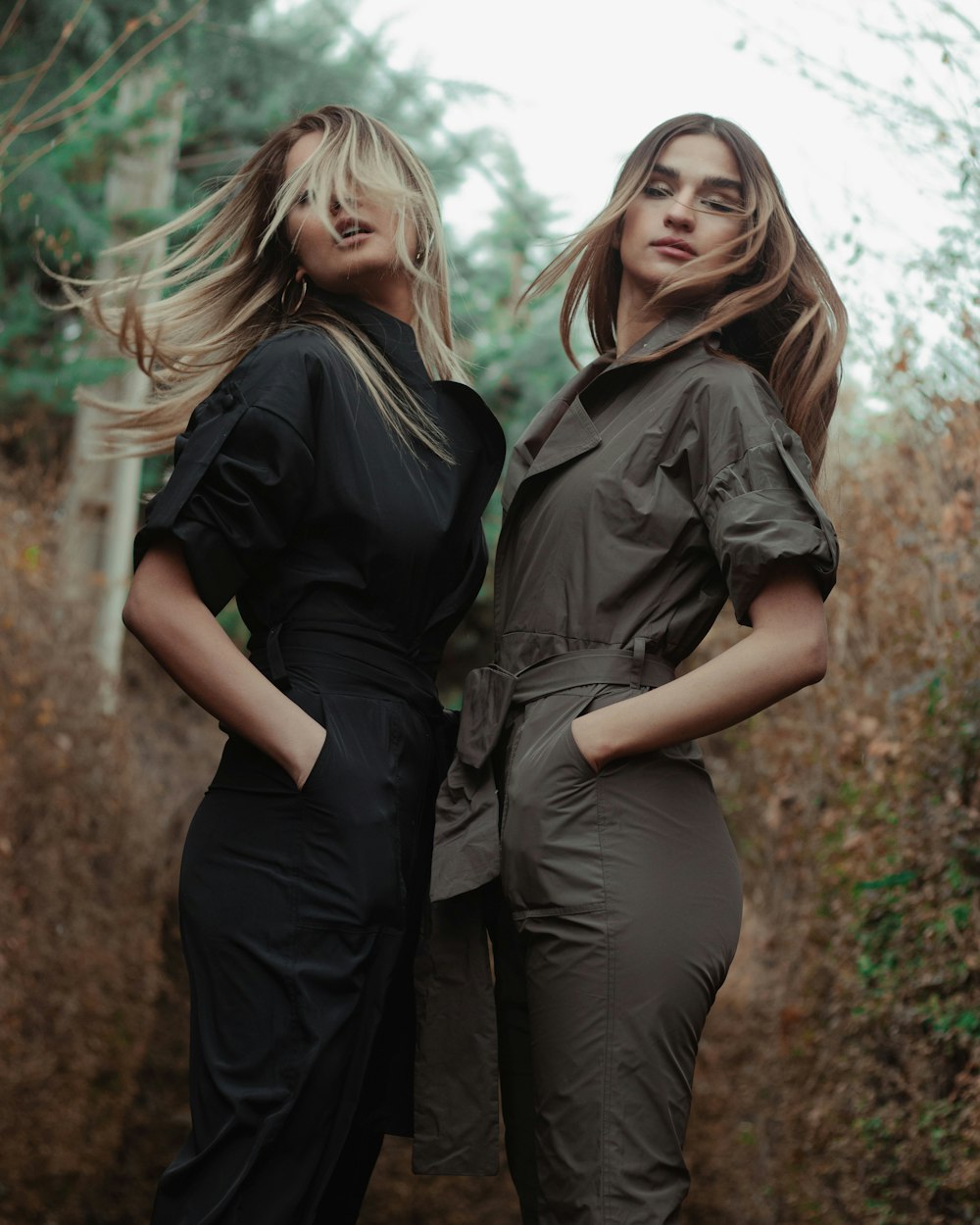 2 women in black shirt and gray pants standing on brown grass field during daytime