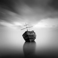 An ancient, weathered sailing ship silhouette drifting silently through foggy waters.