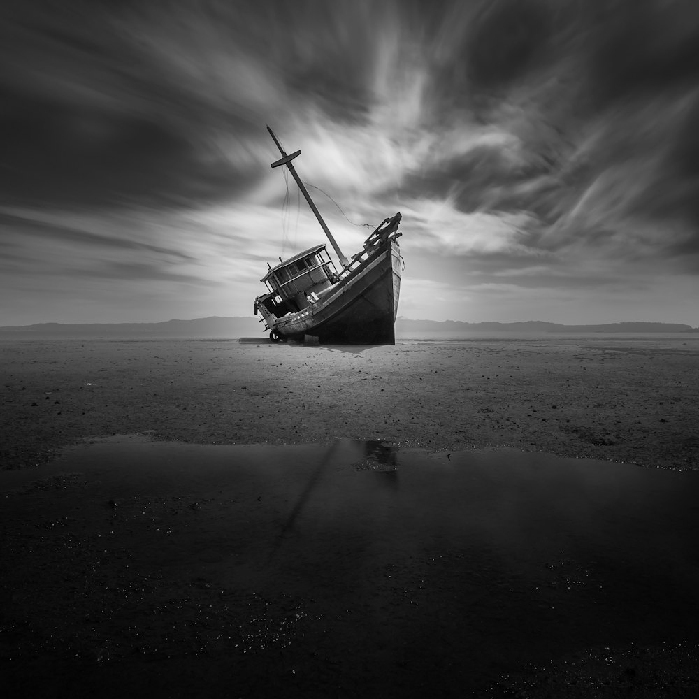 grayscale photo of boat on beach