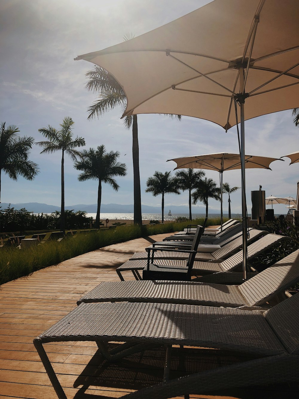 brown wooden outdoor table with chairs and umbrella near green trees during daytime