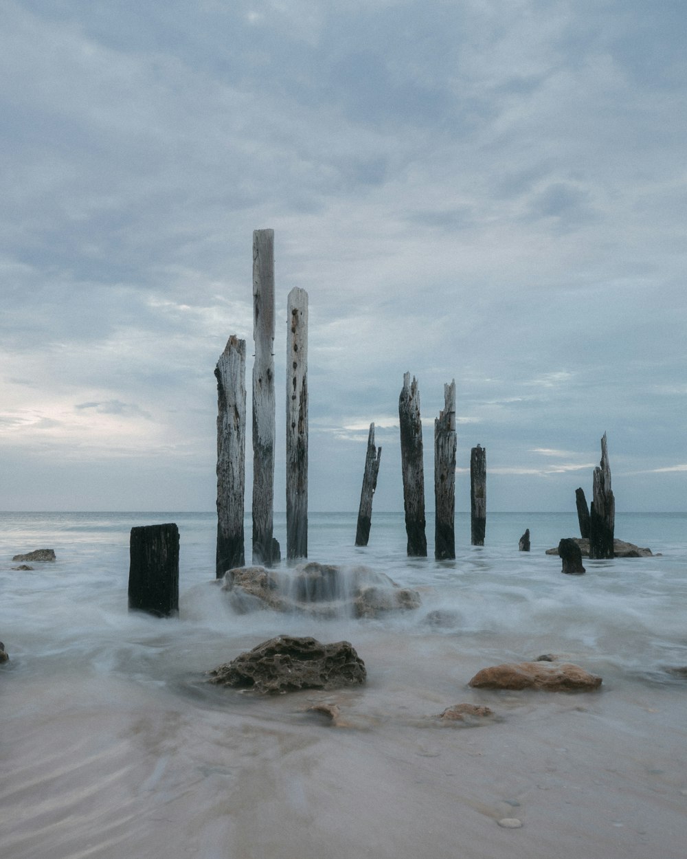 gray wooden poles on white sand beach during daytime