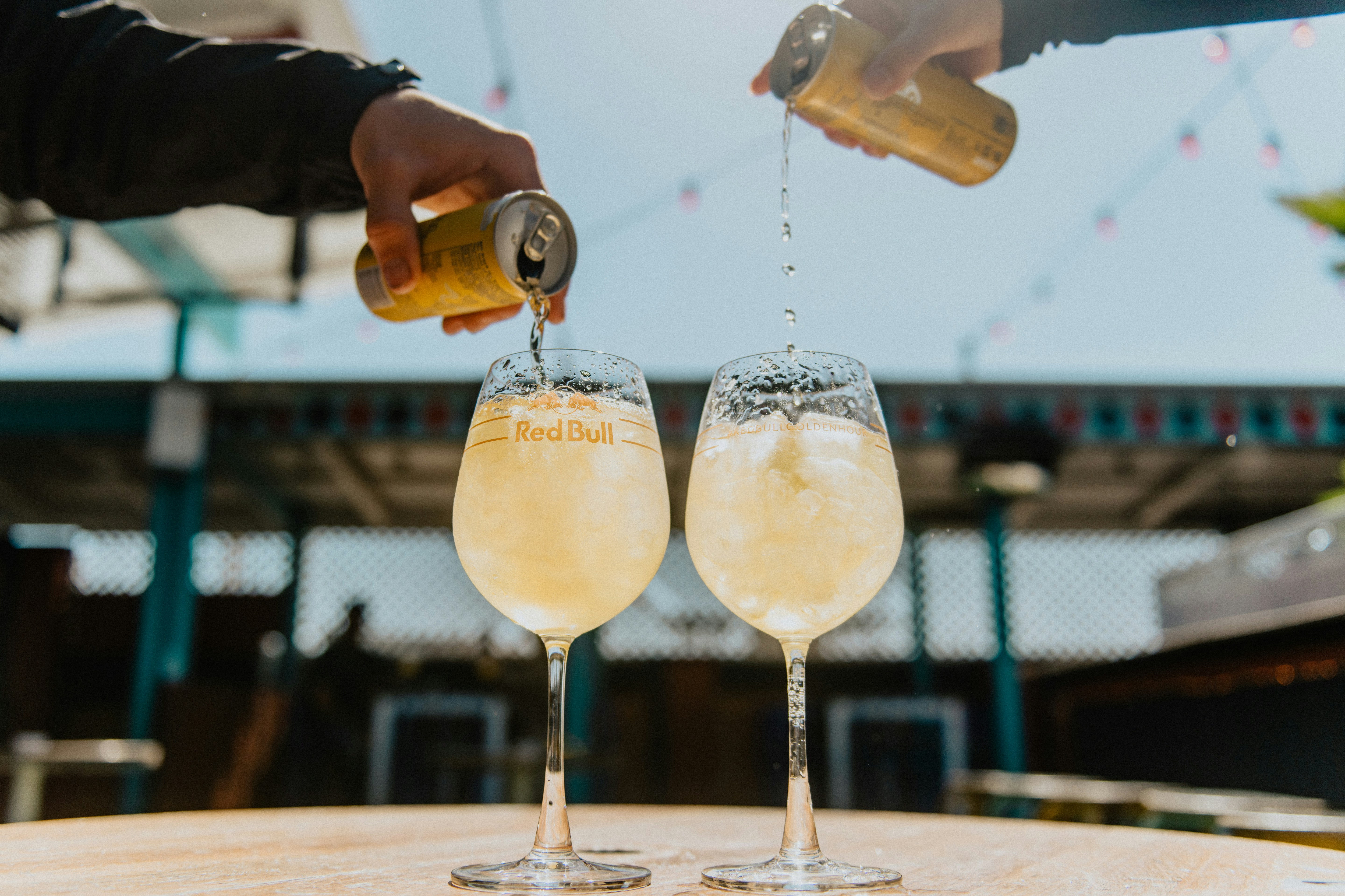 person pouring yellow liquid on clear drinking glass, Redbull Pour