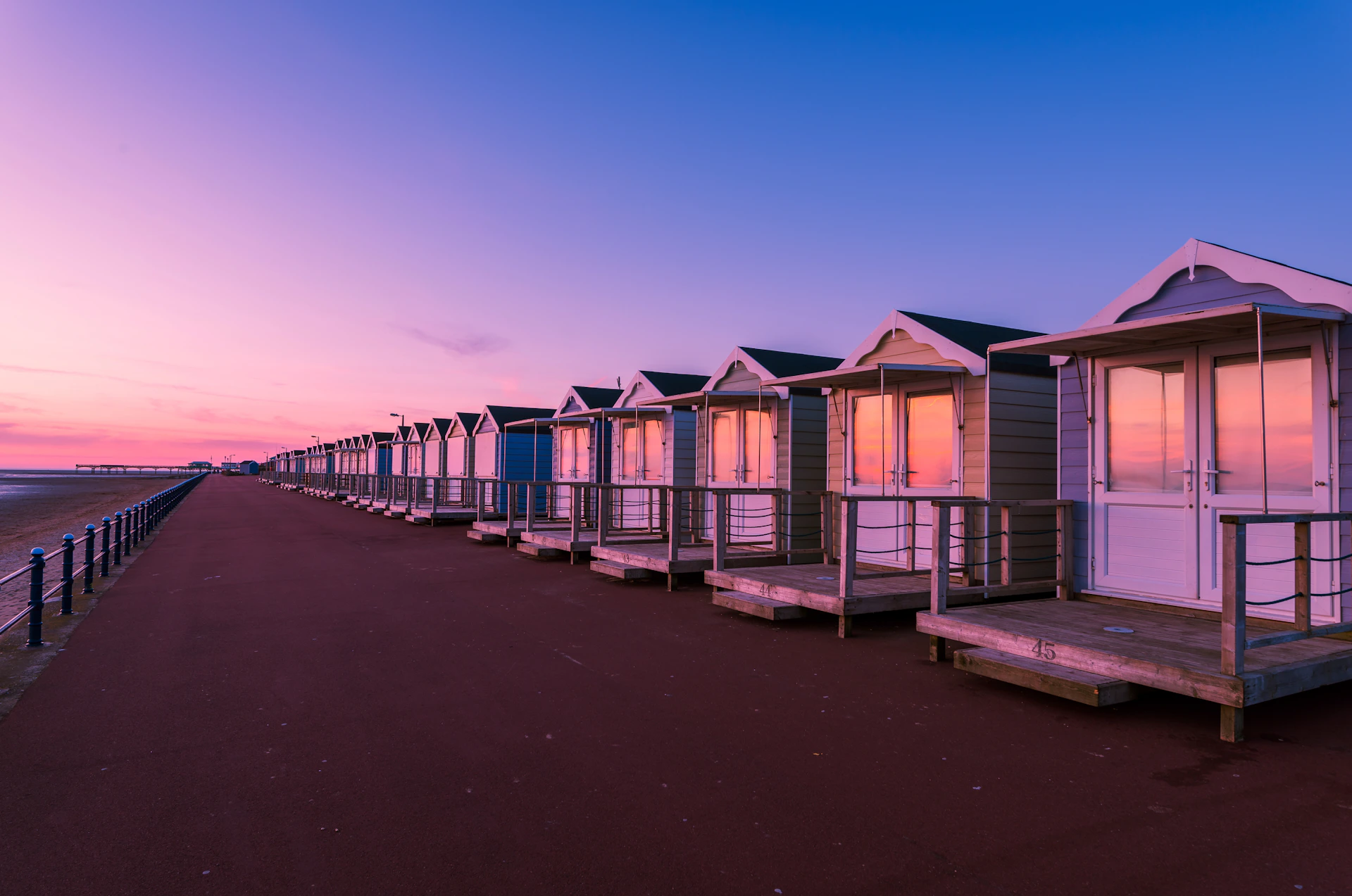a row of beach huts sitting on top of a sandy beach