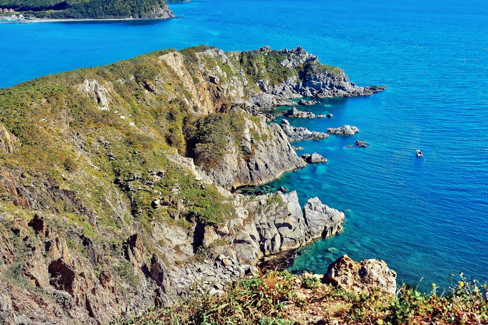 green and brown rock formation beside blue sea during daytime