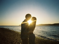 A silhouette of a couple enjoying a sunset on the beach.