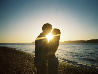 A cinematic still of a couple embracing at sunset on a beach.