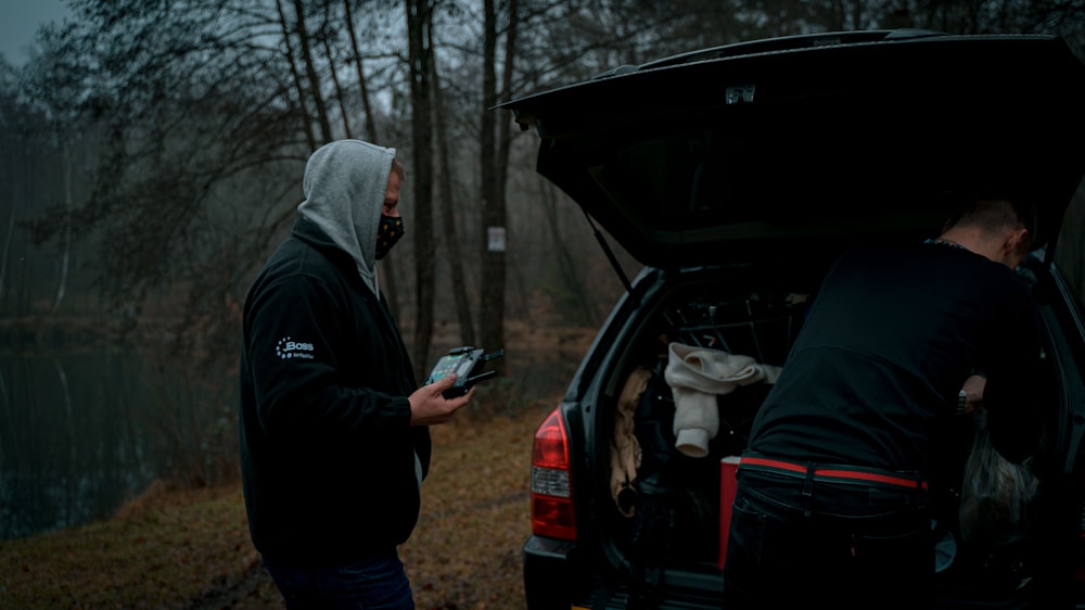 man in black jacket standing beside car