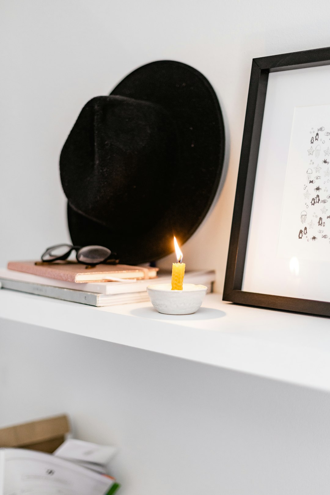 black fedora hat beside white candle on brown wooden table