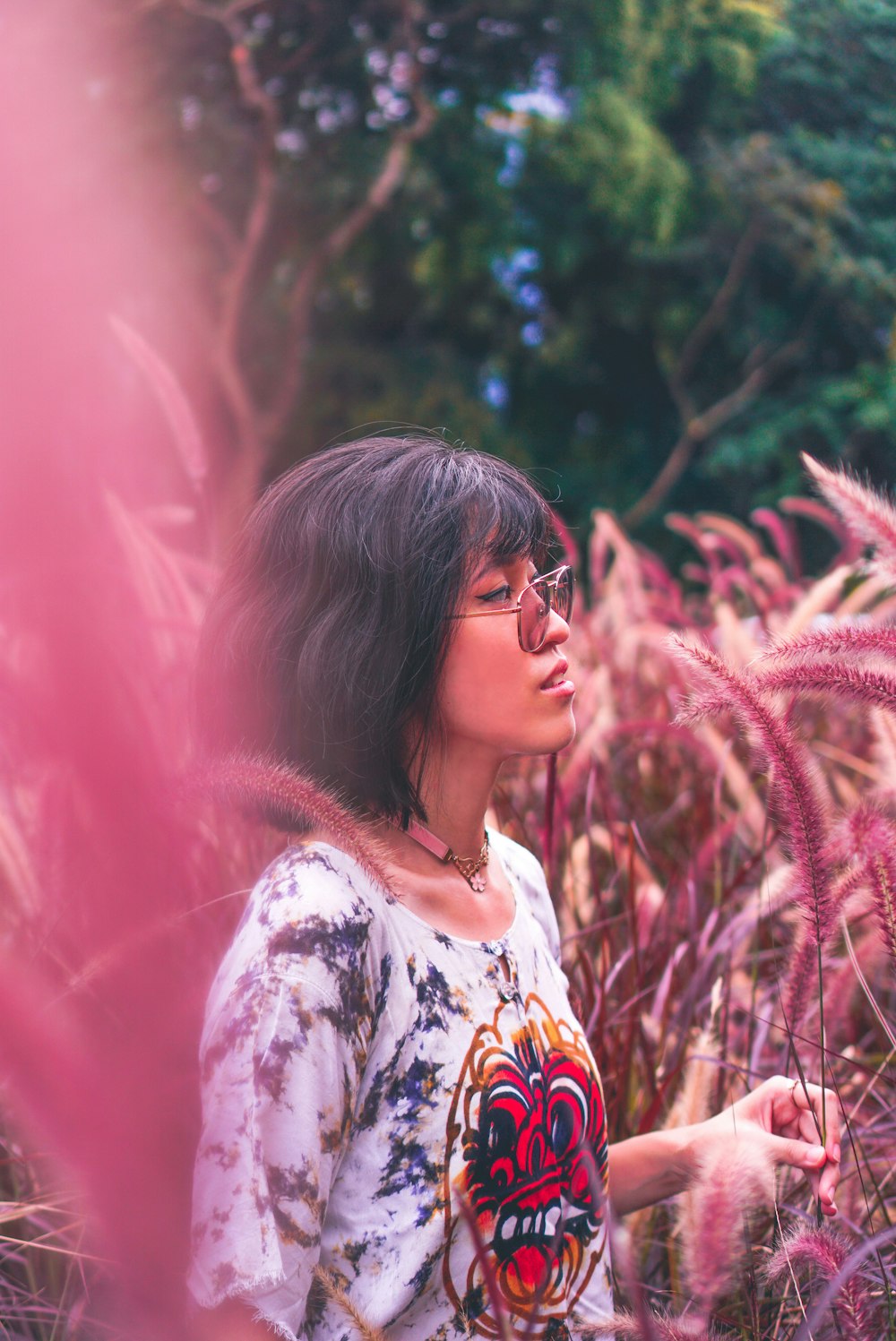 woman in white and yellow floral shirt standing near green plants during daytime