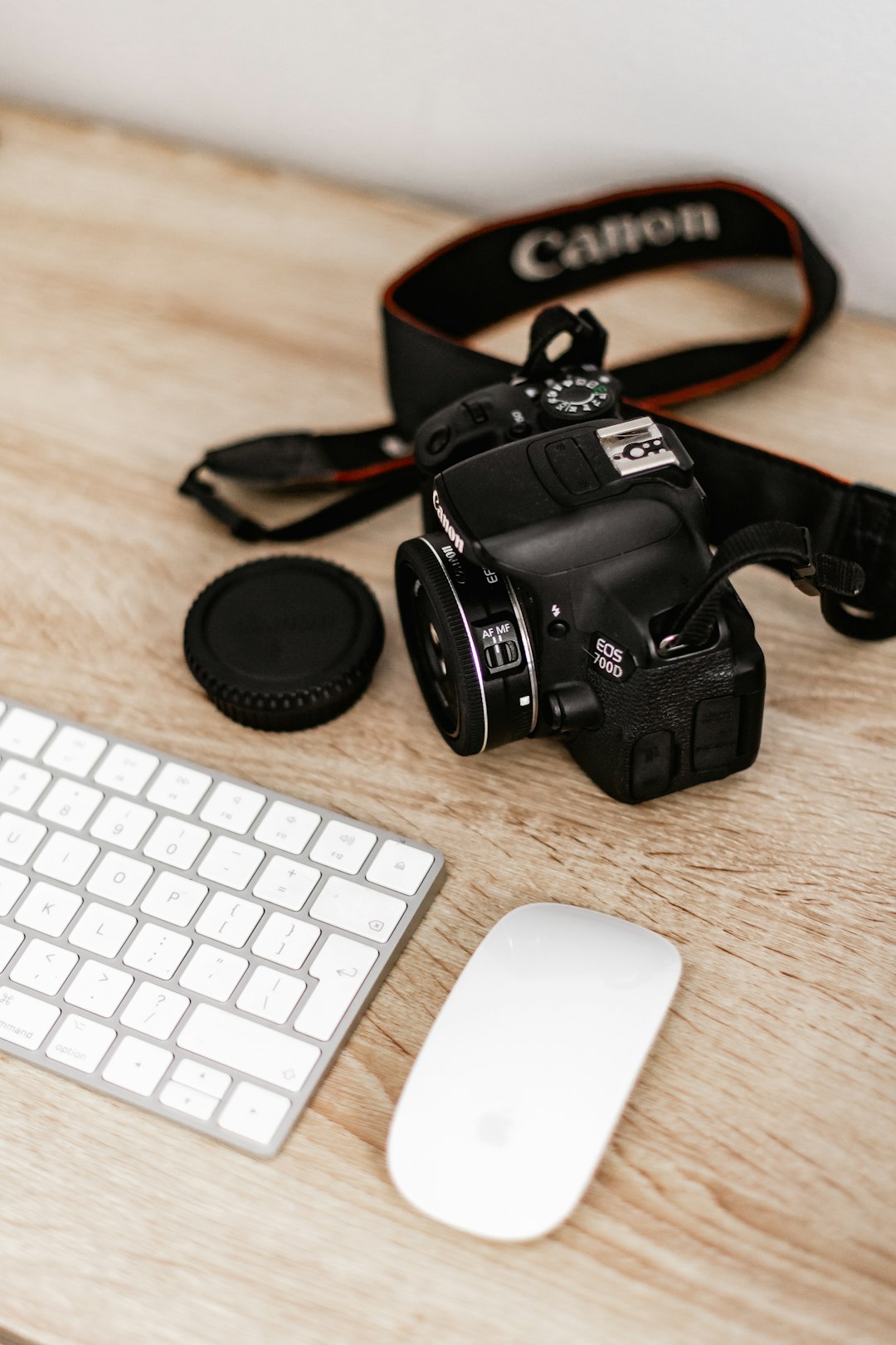 black nikon dslr camera beside white apple magic keyboard