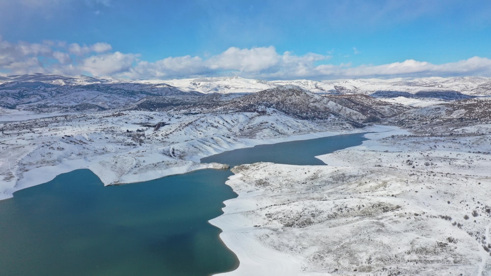 snow covered mountain near lake under blue sky during daytime