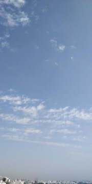 An open plot of empty land with clear blue sky and city skyline in the background.