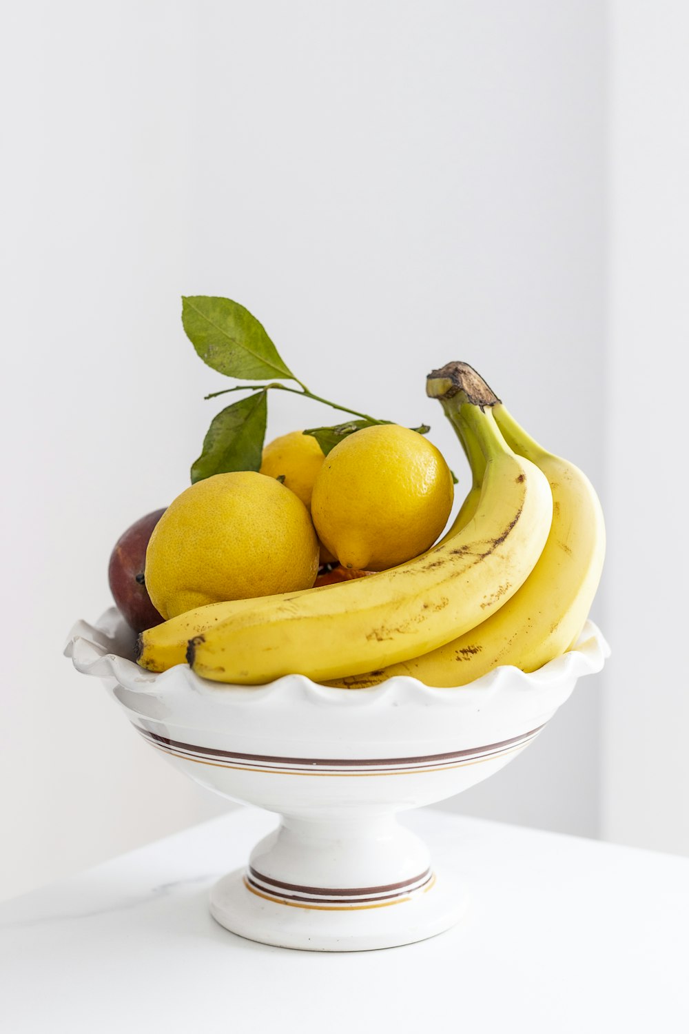 fruta amarela da banana na tigela cerâmica branca