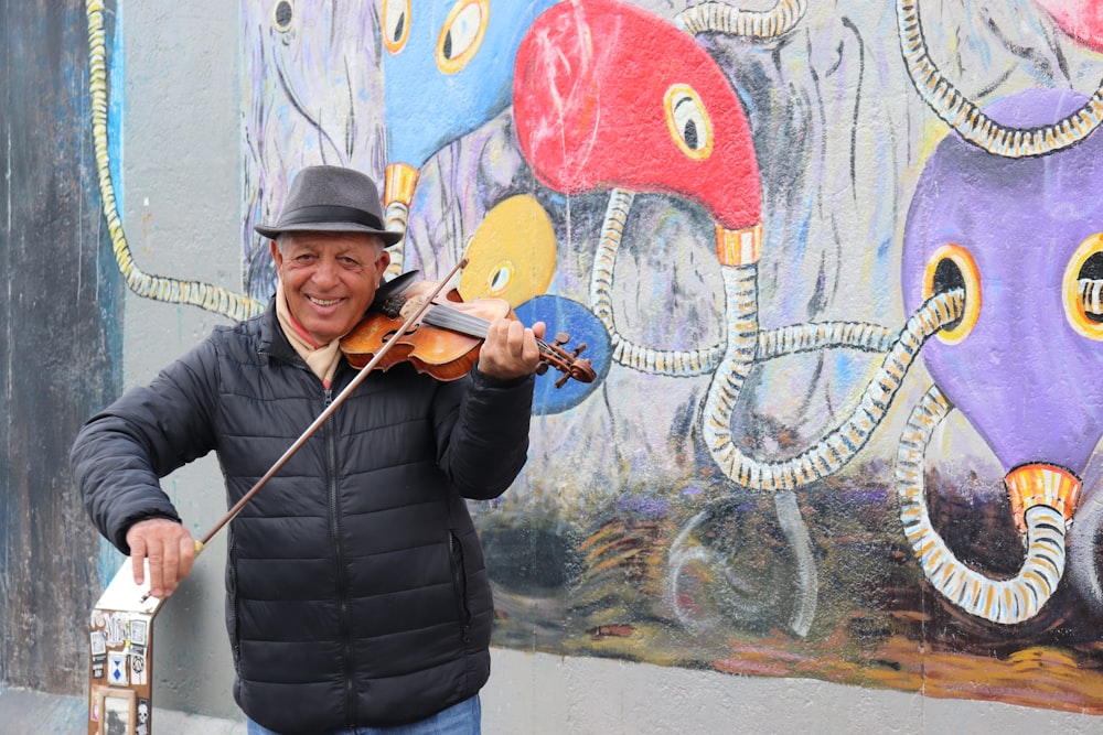 man in black bubble jacket holding brown violin