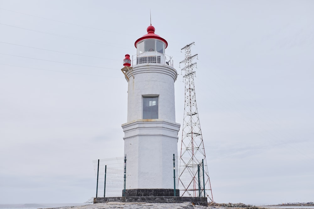 white and red concrete lighthouse under white sky during daytime