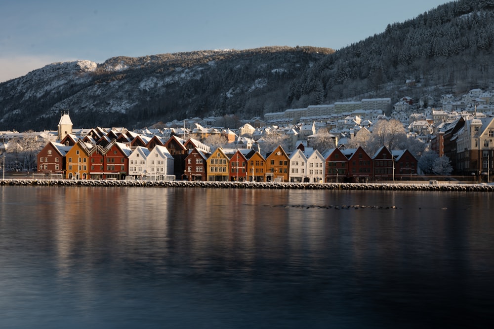 brown and white wooden house near body of water and mountain