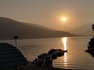 A tranquil lake surrounded by fishing boats at sunset.