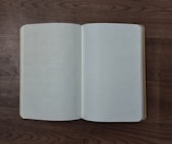 An open notebook with dot grid pages rests on a wooden surface, capturing a minimalist and organized setting.