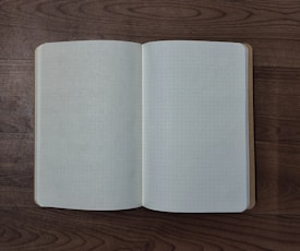 An open notebook with dot grid pages rests on a wooden surface, capturing a minimalist and organized setting.