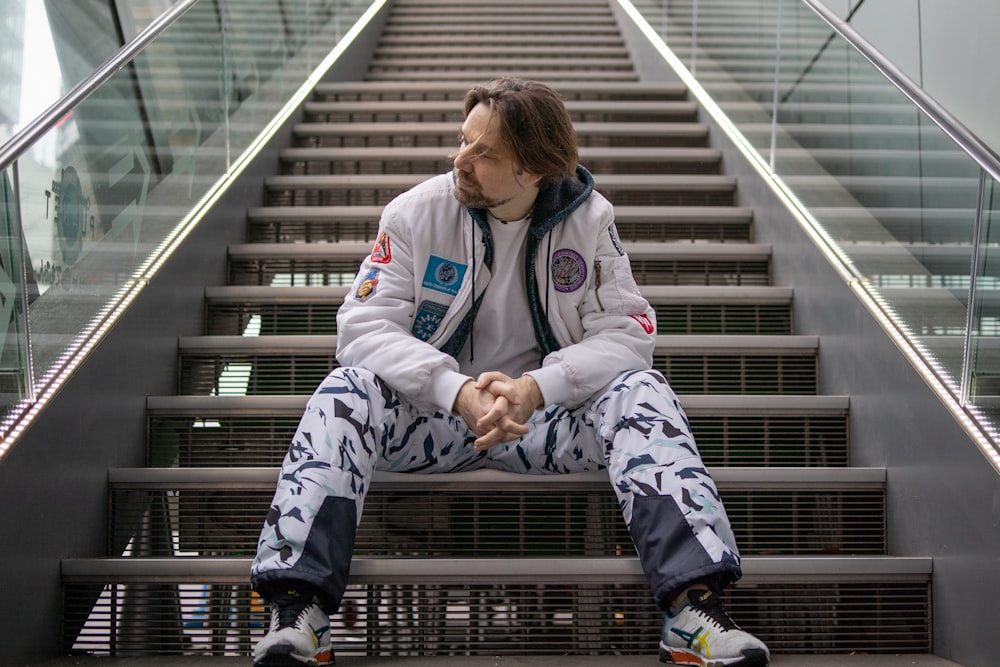 woman in white and blue jacket and pants sitting on black metal railings