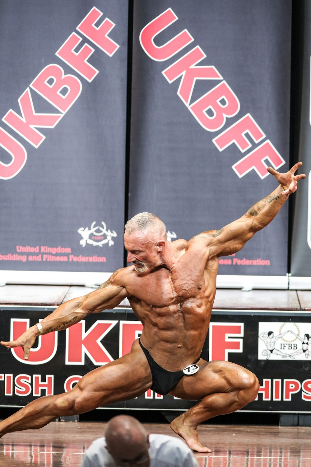 a bodybuilding man doing a trick on a wooden floor